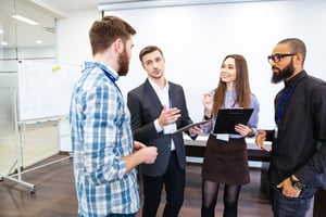 Head of department standing and talking to smiling young employees in office
